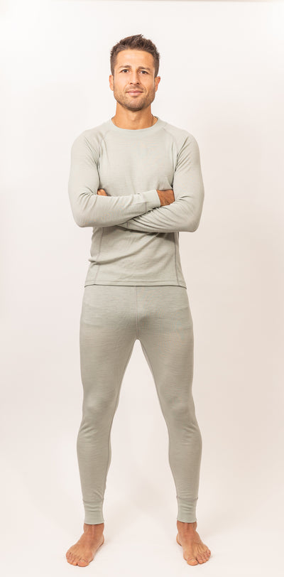 Hombre de pie con postura relajada vistiendo Primera Capa Pantalón Hombre 100% Lana Merino color gris claro.