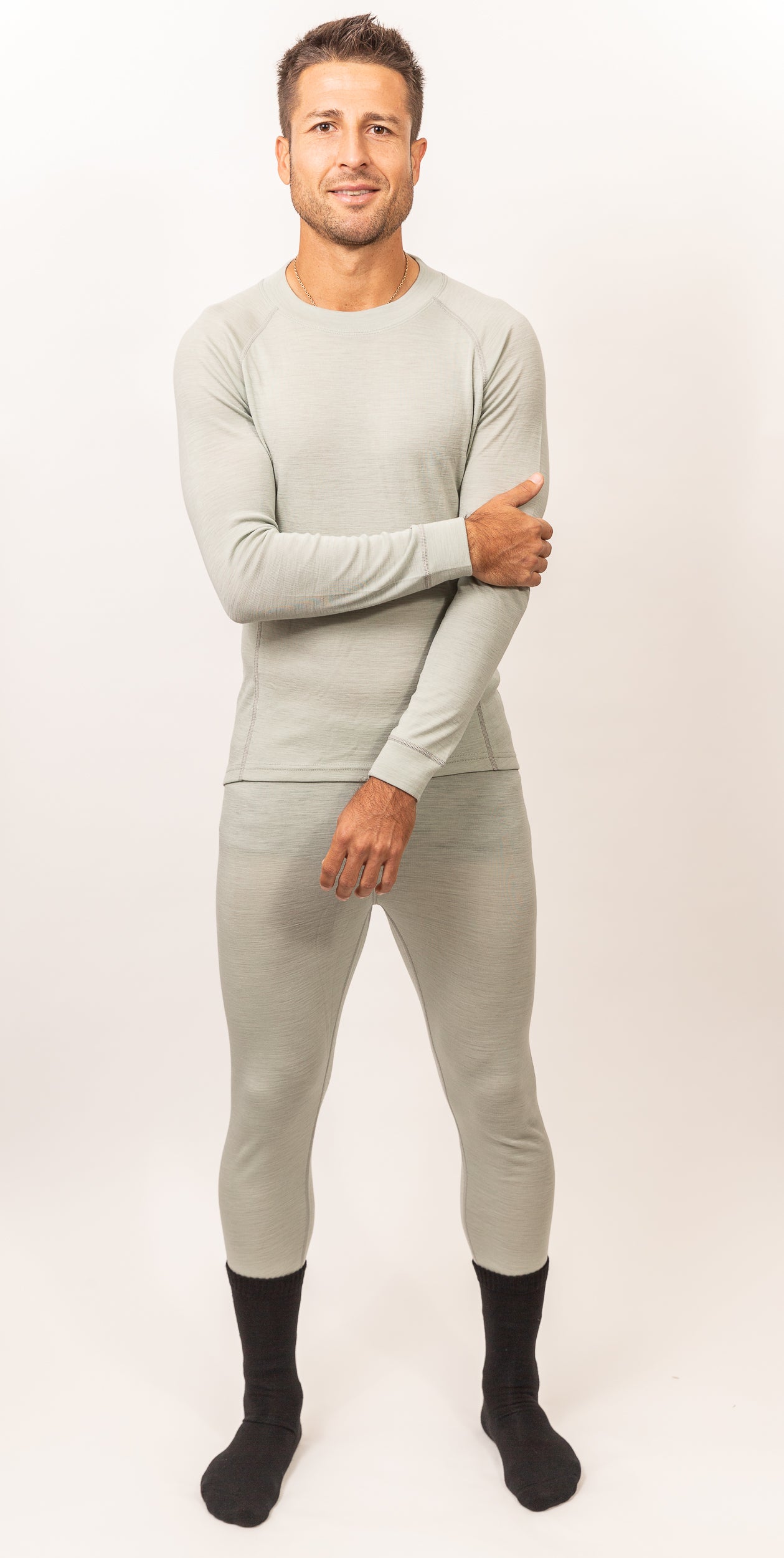 Hombre con ropa interior térmica gris clara y calcetas negras posando con fondo blanco y expresión relajada