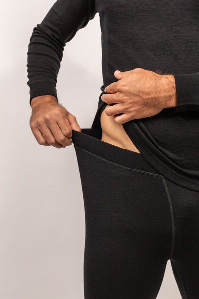 Hombre ajustándose el Primera Capa Pantalón Hombre 100% Lana Merino mostrando elasticidad y comodidad.