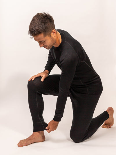 Hombre vistiendo Primera Capa Pantalón Hombre 100% Lana Merino negro ajustado y cómodo en postura activa