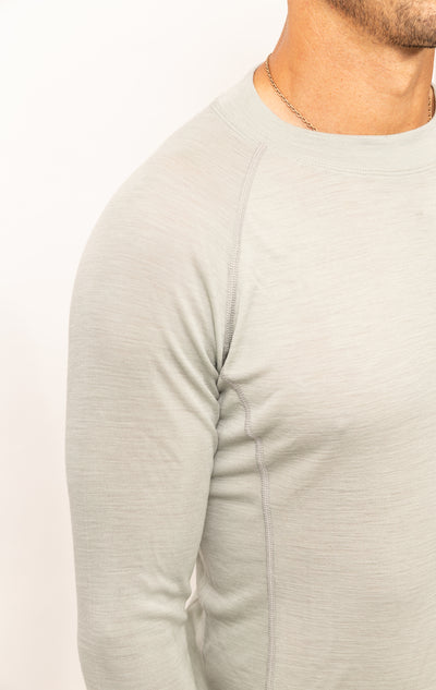 Detalle del torso de hombre con suéter de lana merino color claro que resalta comodidad y calidad.