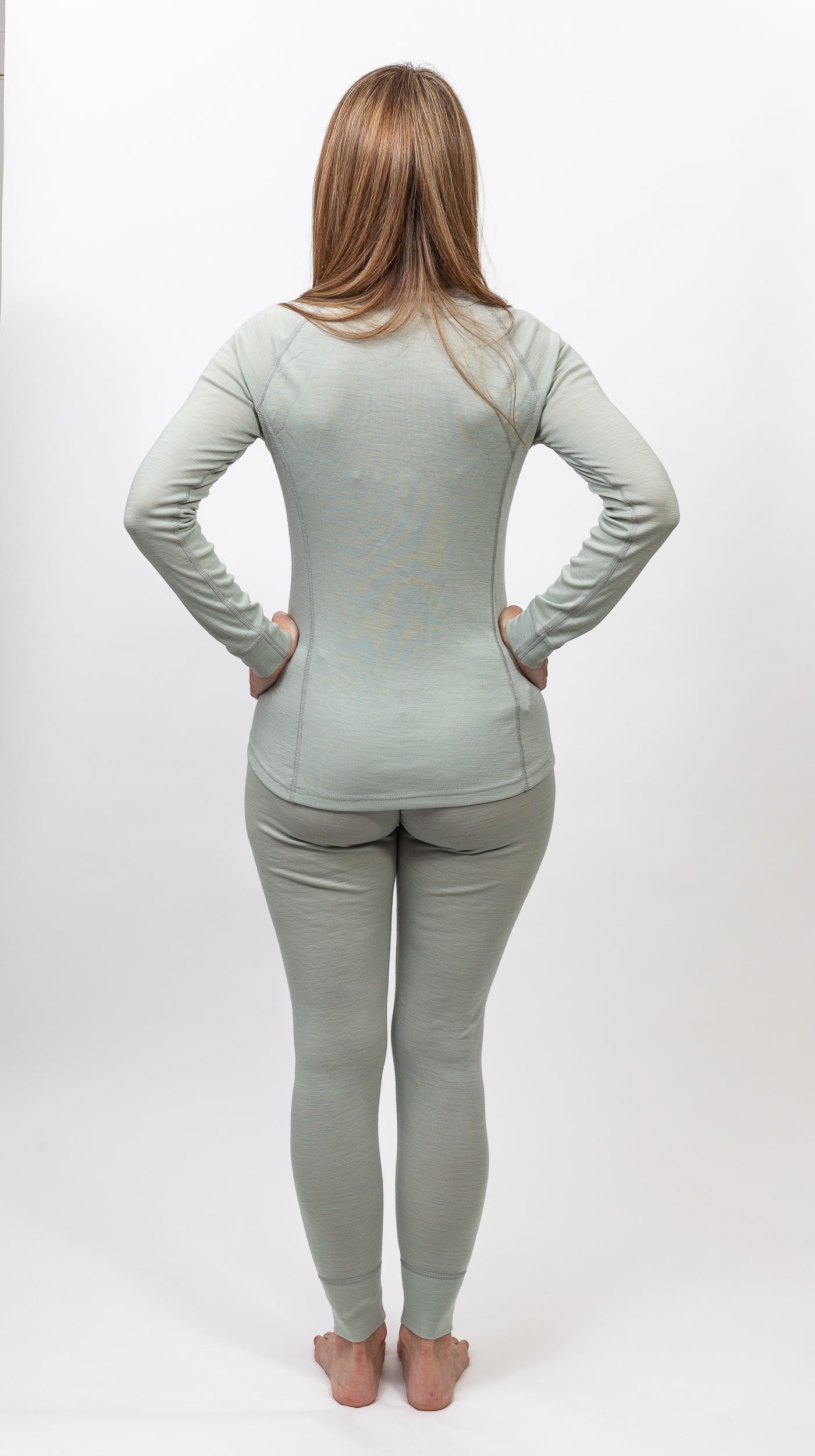 Mujer de espaldas usando conjunto ajustado color gris claro en fondo blanco, mostrando comodidad y calidad.